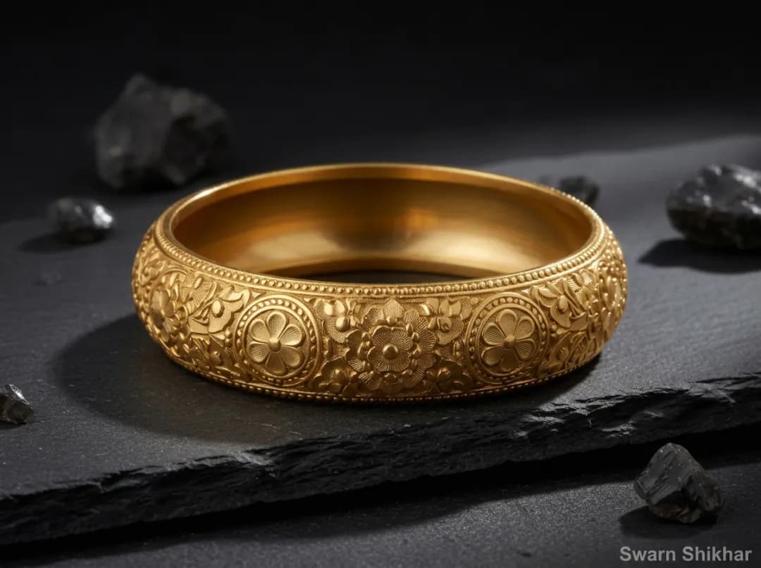 A repaired and polished engraved gold kada standing perfectly round on slate